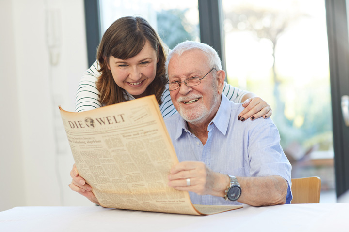 Die Geschenkzeitung: Zeitung zum Geburtstag. Glücklicher Vater freut sich über seine Geburtszeitung! Ein Geschenk, das die Zeit zurückdreht – ein Vater vertieft sich in die Erinnerungen seines Lebens, während seine Tochter mit leuchtenden Augen den Moment genießt. 